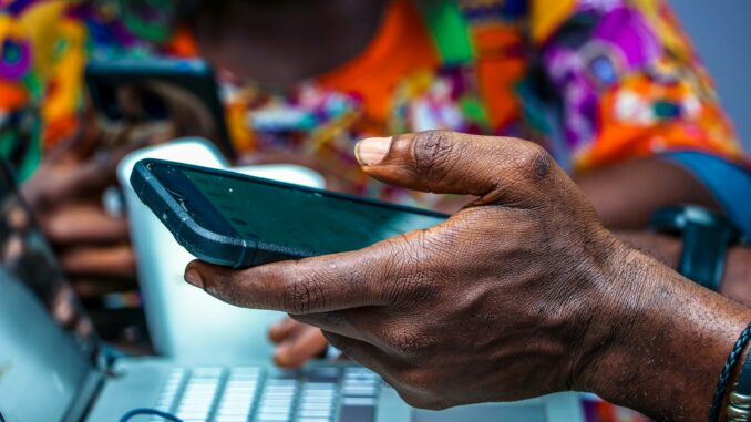 Nigerian man using a smartphone for mobile airtime transfer