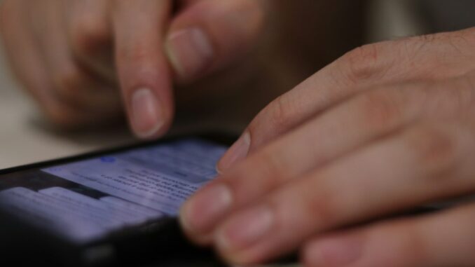 Person checking a smartphone for mobile connectivity. Photo by Alicia Christin Gerald on Unsplash.