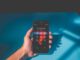 Person holding an iPhone while using a mobile service. Photo by Quilia on Unsplash.