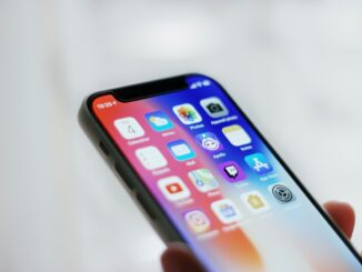 Person holding a black iPhone for mobile data access. Photo by Adrien on Unsplash.